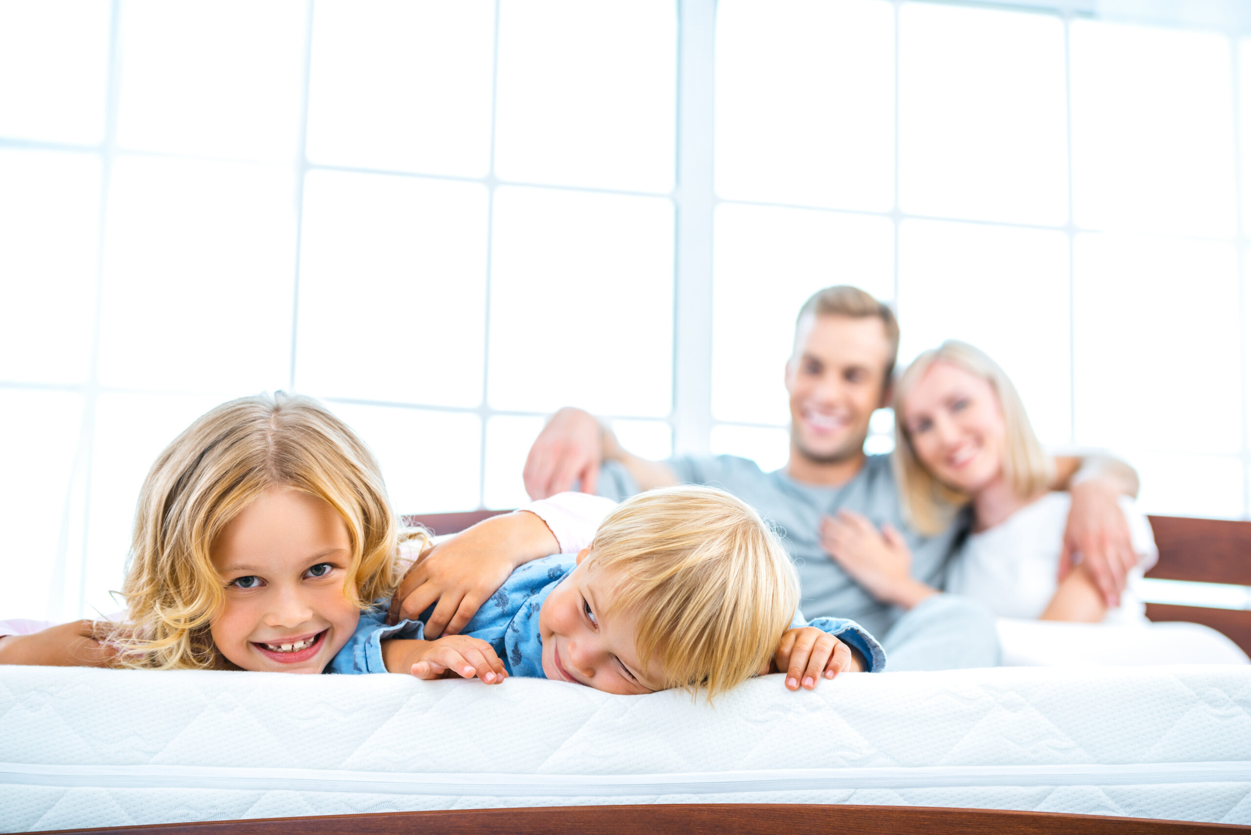 Image of Young family lying on white bed